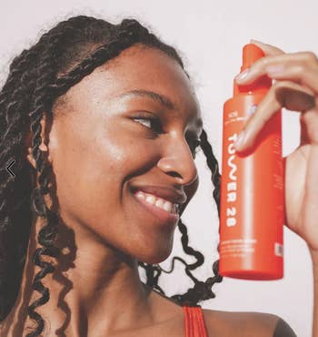 model holding the red bottle of facial spray