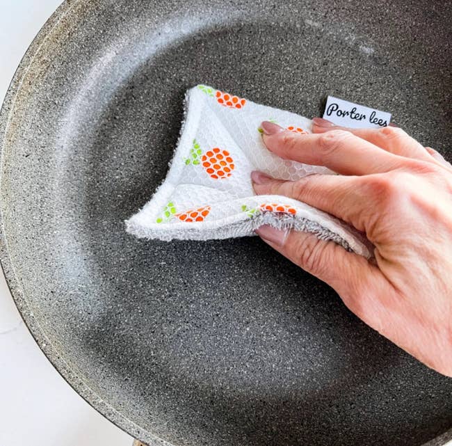 hand using sponge on a pan 