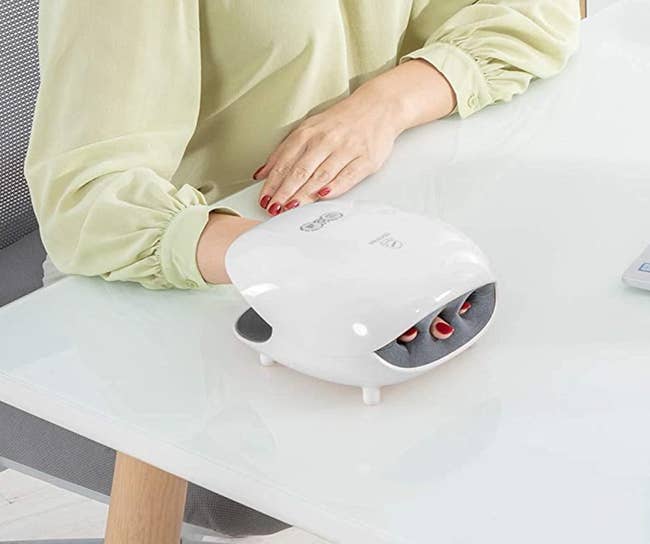 Model with their hand in a white device with slots for fingers