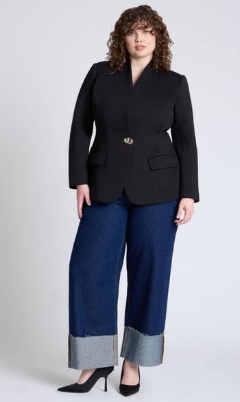 Person successful  a stylish achromatic  blazer, wide-leg jeans with rolled cuffs, and achromatic  heels, posing for a manner  buying  article