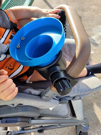 another reviewer's photo of the blue tray in a cupholder attached to a stroller