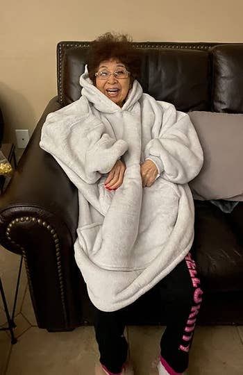Reviewer's grandma wearing the blanket in color blush, smiling