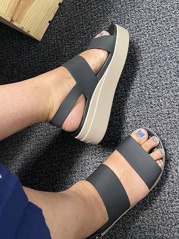 Person trying on black platform sandals with a thick sole
