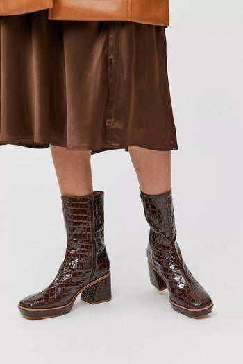 a model wearing brown alligator-printed platform boots