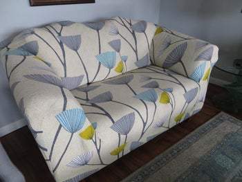 reviewer photo of their sofa after adding the patterned slipcover