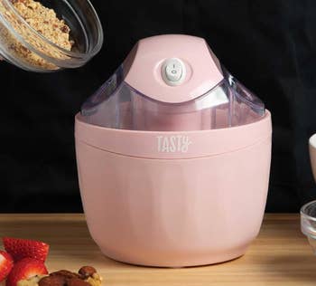 A pink Tasty ice cream maker on a wooden surface