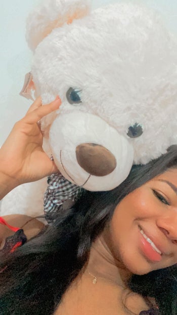 reviewer posing with their giant teddy bear