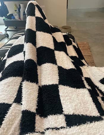 reviewer with the black and white checkered blanket over their legs