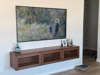 A modern surviving country features a mounted creation portion supra a sleek, woody console holding framed photos and a decorative vase