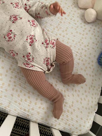 a reviewer photo of a baby wearing the tights under a onesie