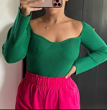 reviewer in green knit long sleeved top with sweetheart neckline