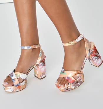 a model wearing the shoes featuring a pastel floral print 