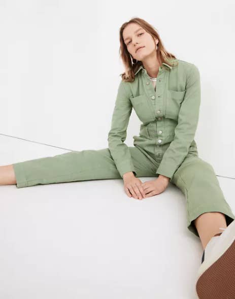 a model wearing the jumpsuit in green with buttons down the middle