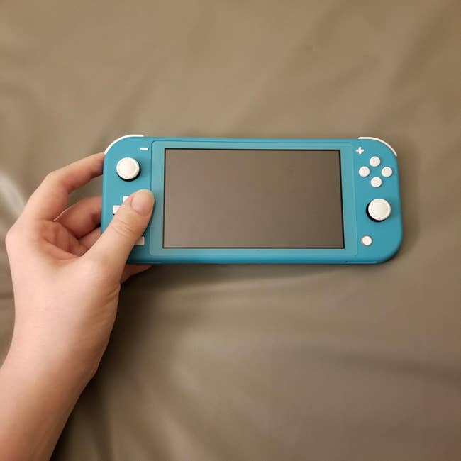 A reviewer holding the handheld game system