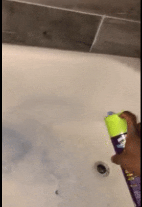 Reviewer spraying blue cleaner on a tub 
