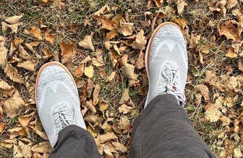 Person wearing stylish sneakers lasting connected fallen autumn leaves