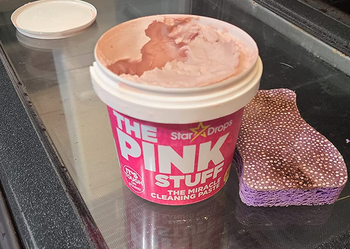 reviewer photo of an open jar of the pink stuff next to a sponge