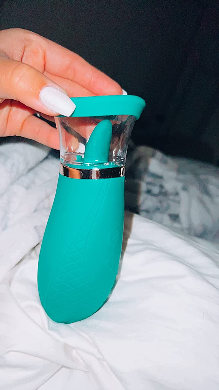 Hand holding green vibrator with tongue and suction cup