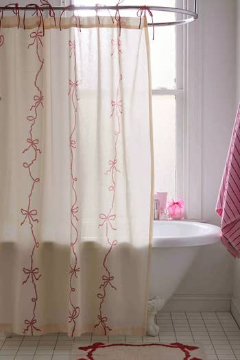 A bathroom scene with a closed shower curtain featuring a vine pattern, beside a bathtub and a coordinating floor mat