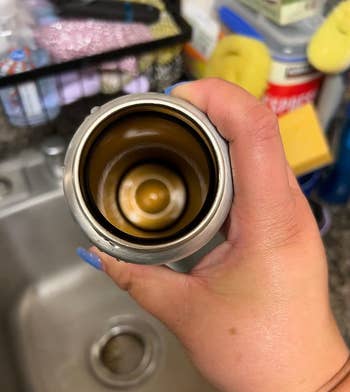 before image of reviewer holding up dirty stainless steel travel mug
