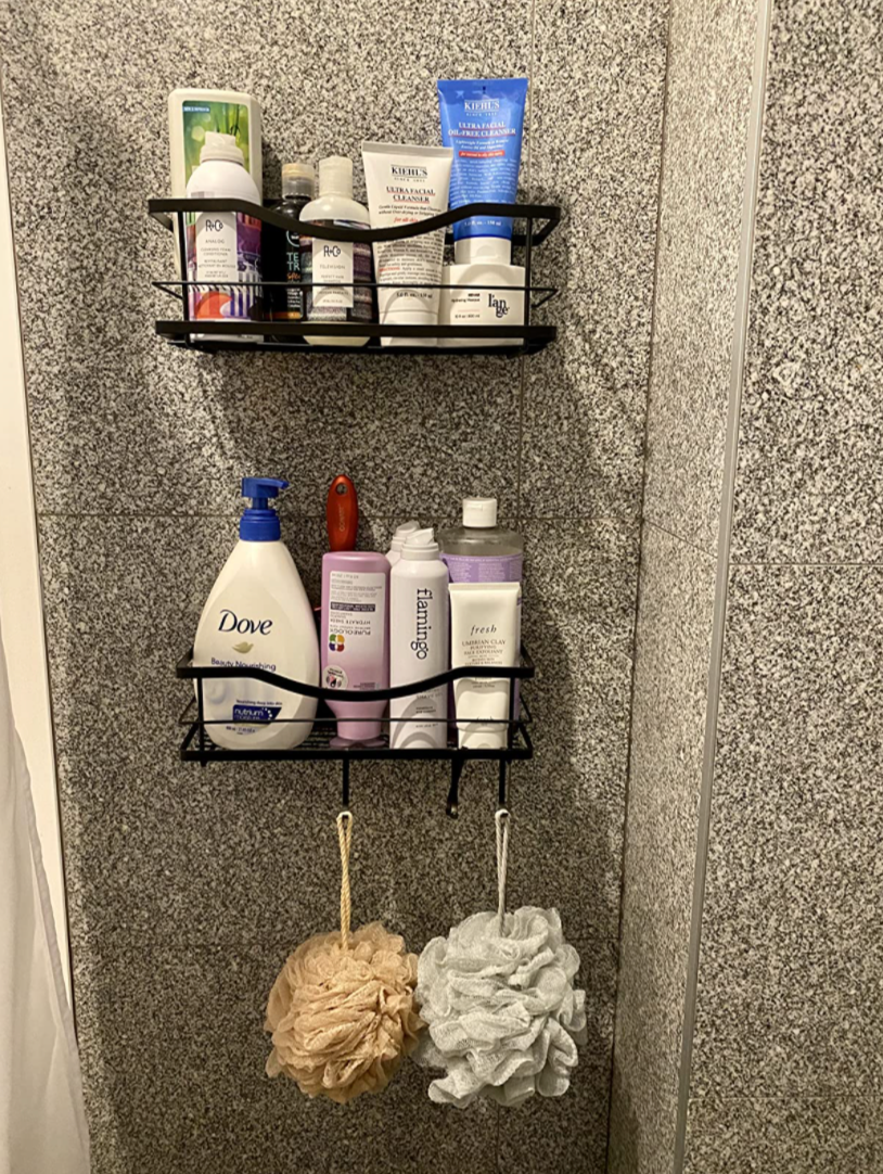 Reviewer image of black shelves attached to a shower wall with lots of products in them 