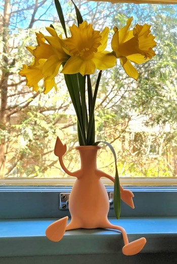 A beige color small vase with four stretchy limbs that bend to sit on a windowsill 
