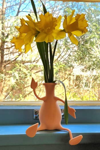 A beige color small vase with four stretchy limbs that bend to sit on a windowsill 