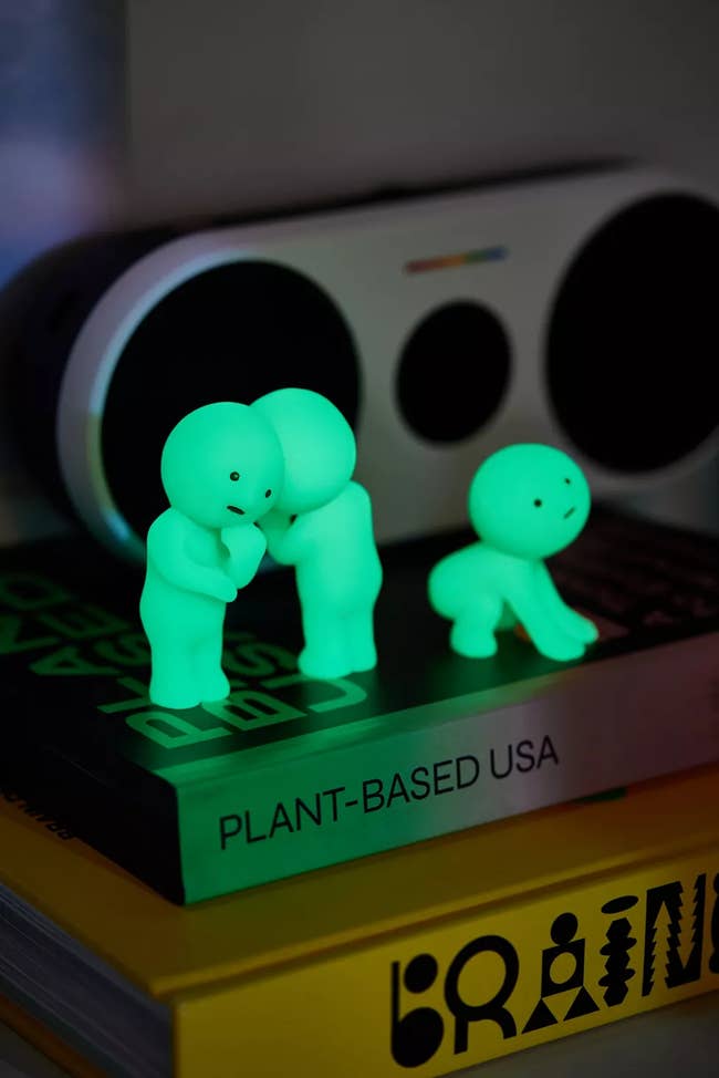 Glowing green figurines are placed on stacked books, including one titled 