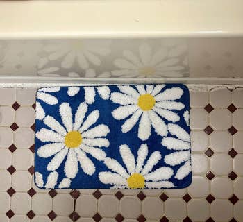 blue floral bath mat with daisy design on a tiled floor