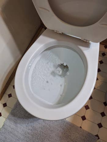 Toilet bowl with water swirling during flushing, seen from above