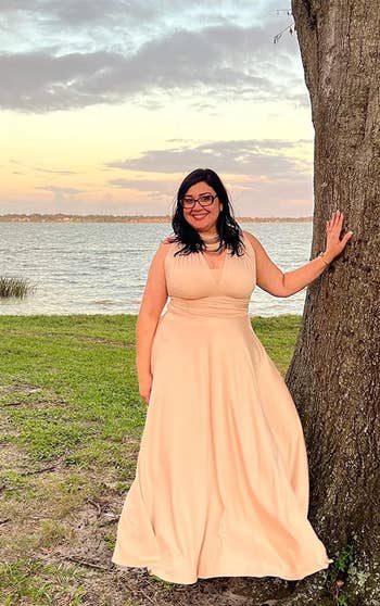A reviewer wearing the dress in peach/light pink 