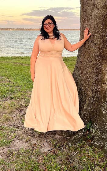 A reviewer wearing the dress in peach/light pink 