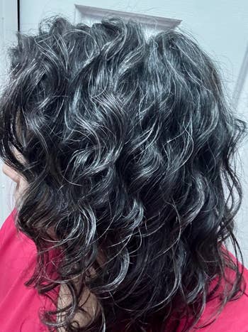 Person with wavy, shoulder-length hair, showcasing a textured hairstyle against a neutral background