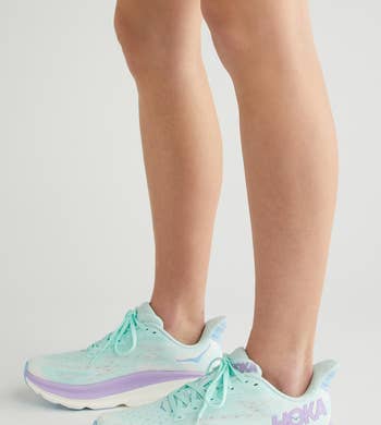 model wearing HOKA athletic shoes in sunlit mist / lilac ocean color