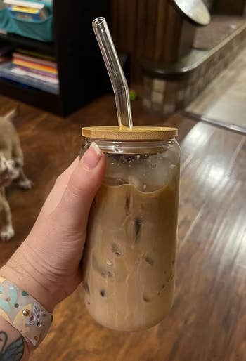 Reviewer holding a mason jar with iced coffee and a reusable straw