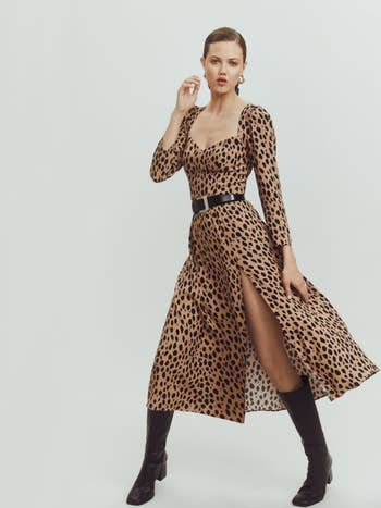a model posing in a brown polka dot midi dress with high boots