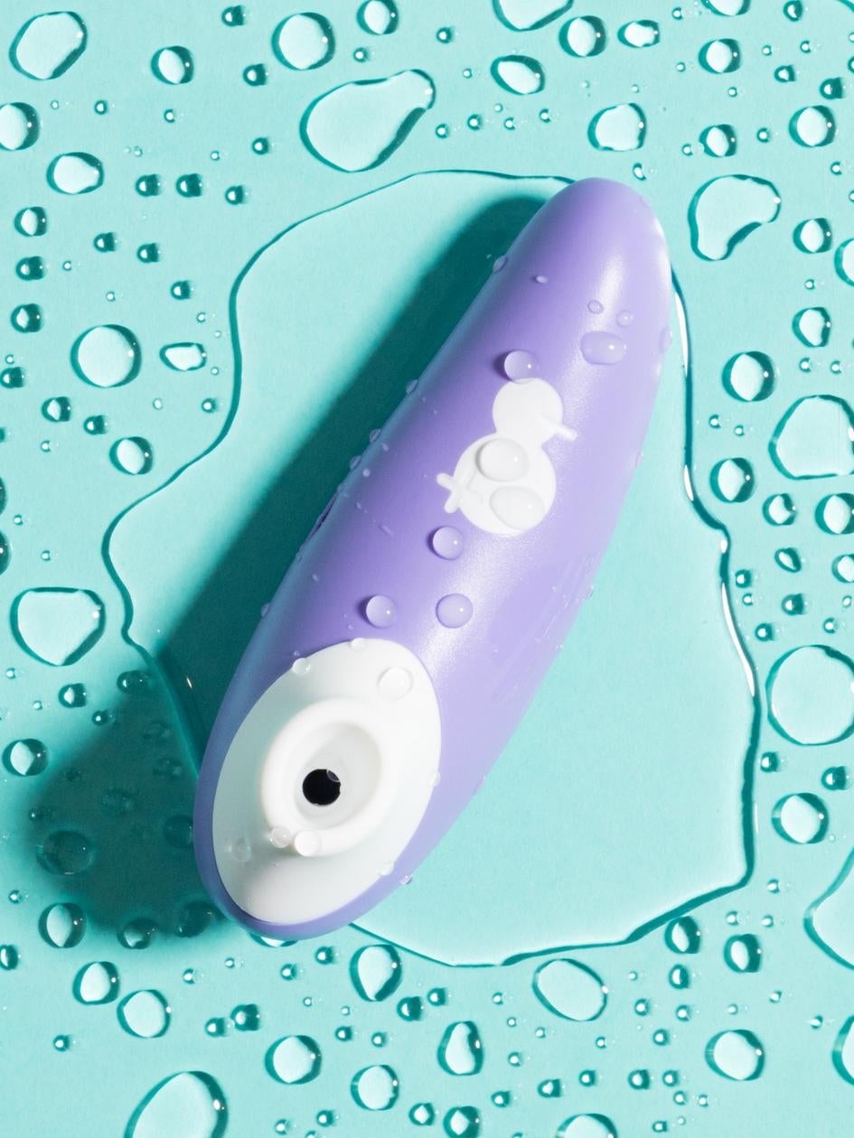 a purple and white suction sex toy on a bed of water droplets