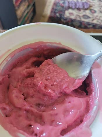 A bowl of pink yogurt with a spoon scooping some out