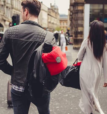 model carries same Trtl pillow attached to a backpack while they travel