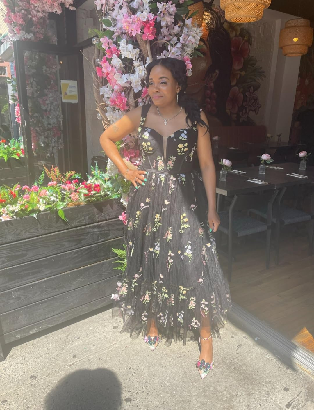 reviewer in evening dress with floral appliqué standing in front of a flower-adorned entrance