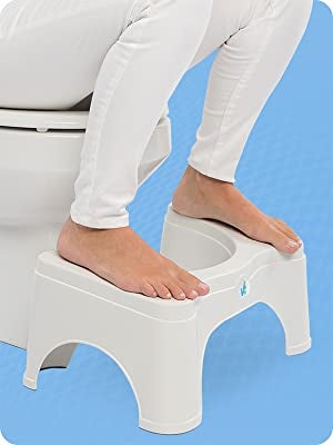 a mannequin sitting on a bathroom with their feet on the squatty potty 