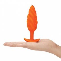 Model holding medium orange butt plug with swirl texture