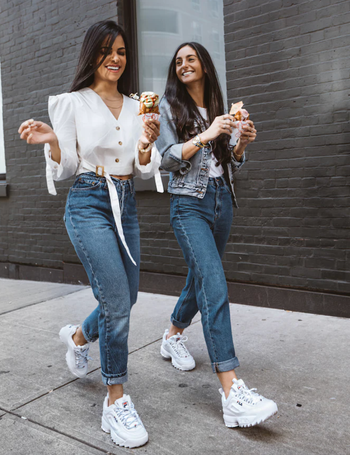 models wearing fila disruptor sneakers while eating ice cream on the sidewalk