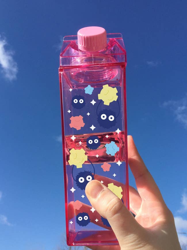 a pink milk carton water bottle with soot sprites all over it