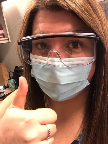 reviewer wearing a mask and clear goggles and giving a thumbs up