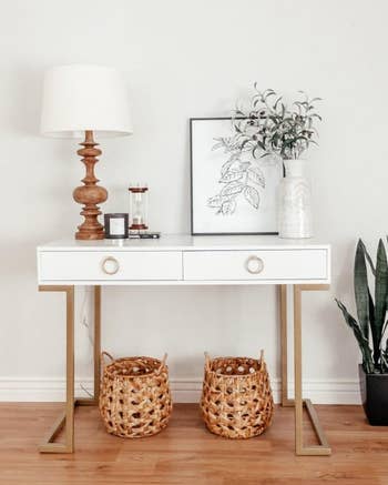 the white desk with a lamp, art, and other decor on it