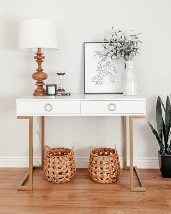 the white desk with a lamp, art, and other decor on it