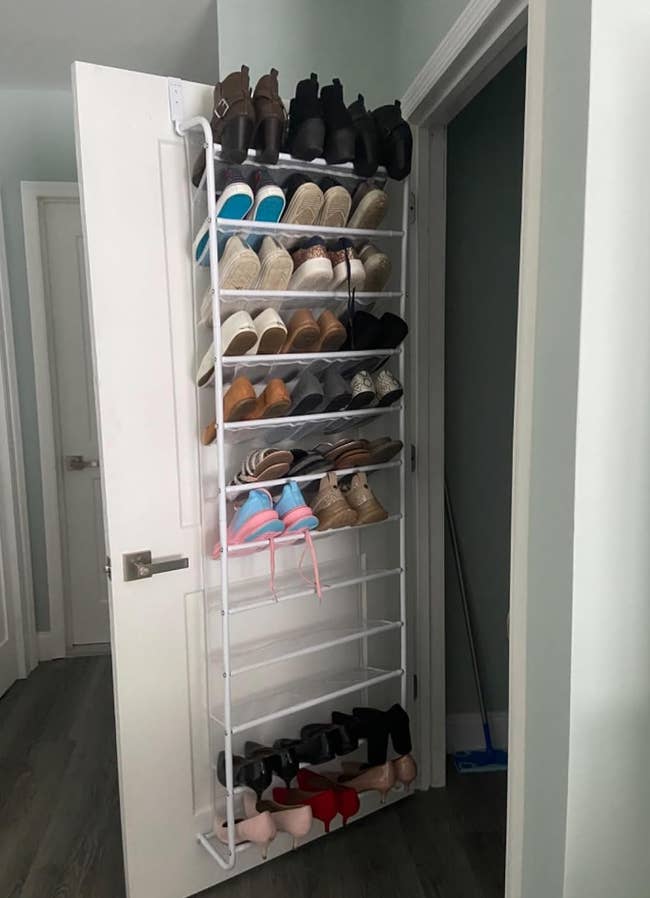 a reviewer photo of the organizer installed on a door with shoes of all types on it 