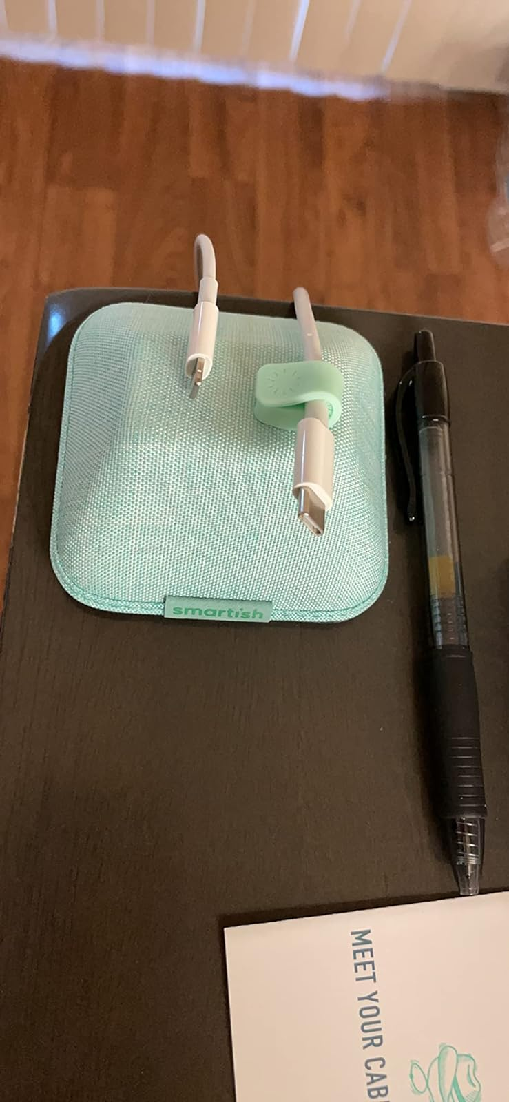 magnetic cable holder in blue on a desk holding two chargers 
