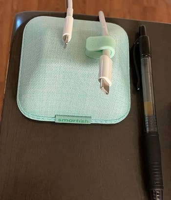 magnetic cable holder in blue on a desk holding two chargers 